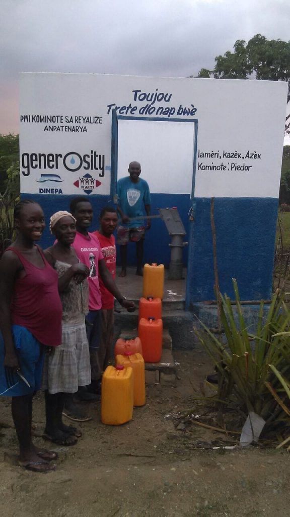 Residents draw potable water from a hand pump.