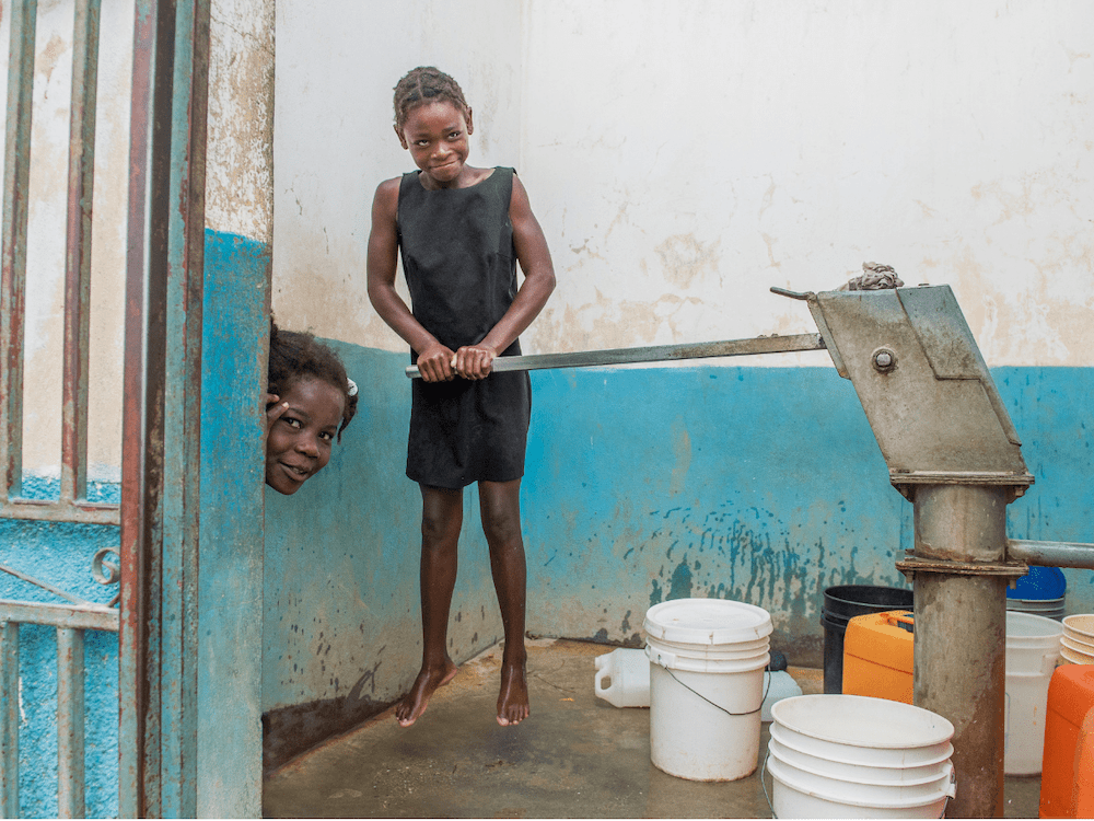 Kids pump potable water from a water source installed by Haiti Outreach and managed by the local community.