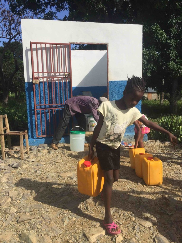 A Haitian girl fetches water from a kiosk.