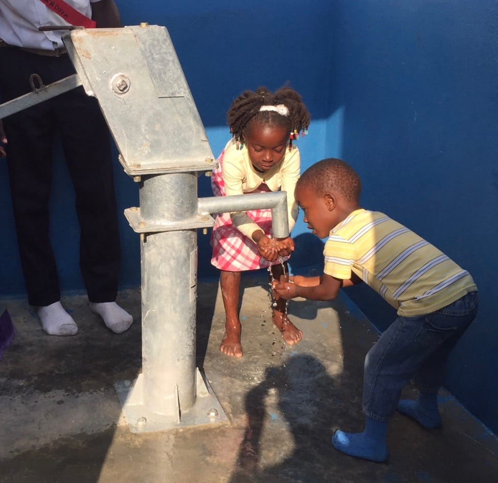 Kids enjoy clean drinking water at a local hand pump.