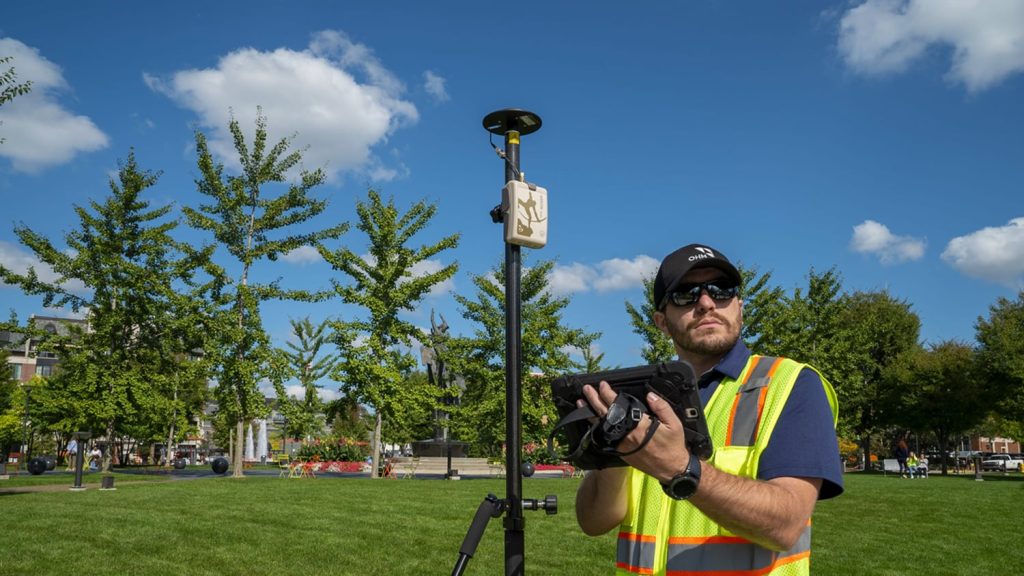A fieldworker performs GIS data collection holding an iPad with an Eos Arrow Gold GNSS / GPS Receiver on a rangepole