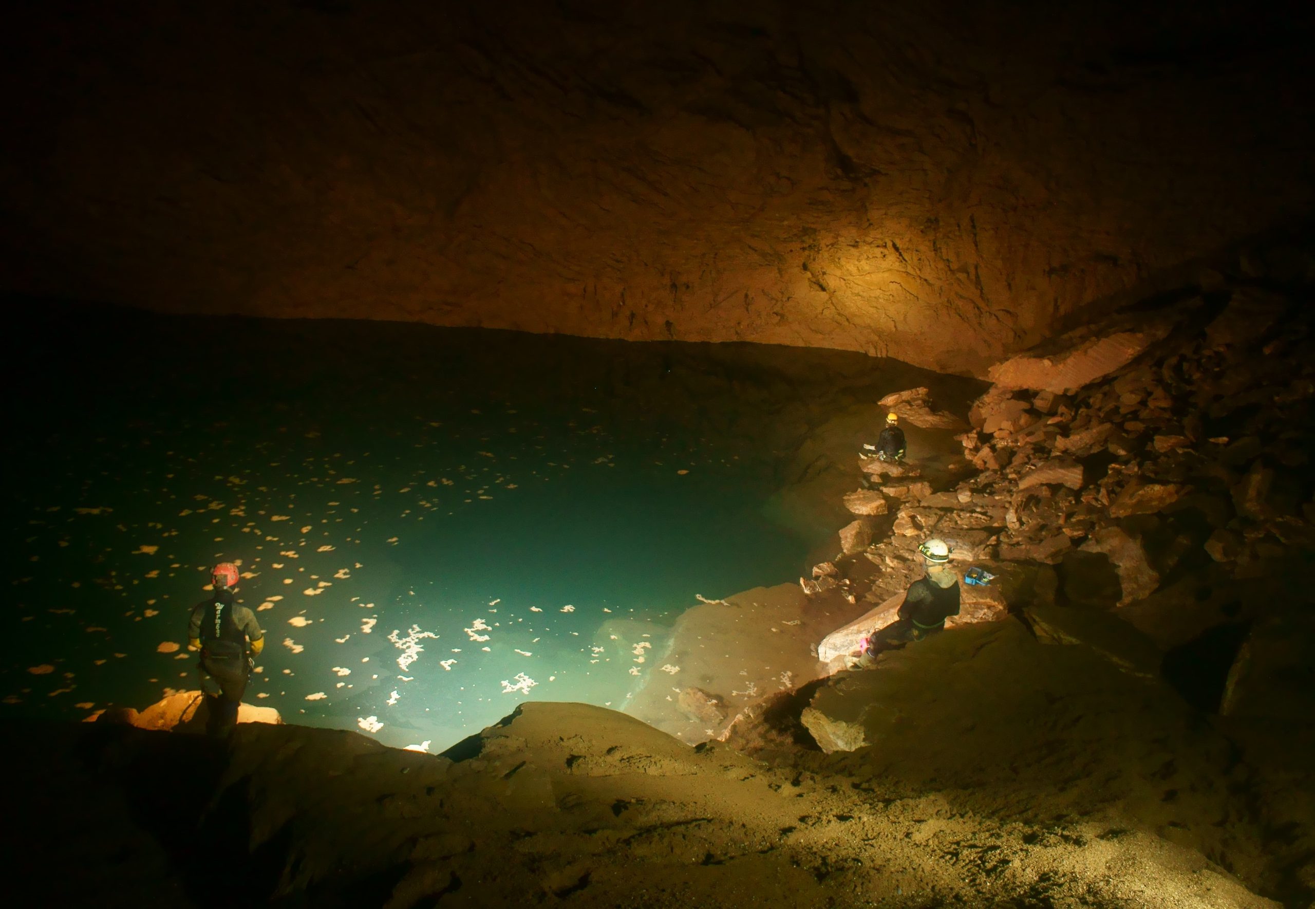 In 1994, a major expedition dove into a deep sump at the lowest point of Sotano de San Agustín. Unfortunately, a British diver drowned. After recovering the body, the team continued its expedition. They found a large passage beyond the sump which led to a much larger and deeper sump, called Sump 9, shown here. Also known as the “Mother of All Sumps,” this became the deepest-known point in Sistema Huautla at that time. Shown here are Mirek Kopertowski, Richard Hudson, and Jon Lillestolen during a 2013 expedition. (Photo by Chris Jewel)